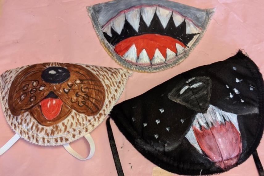 Three painted animal-themed masks: shark, dog, and cat designs on a pale background.