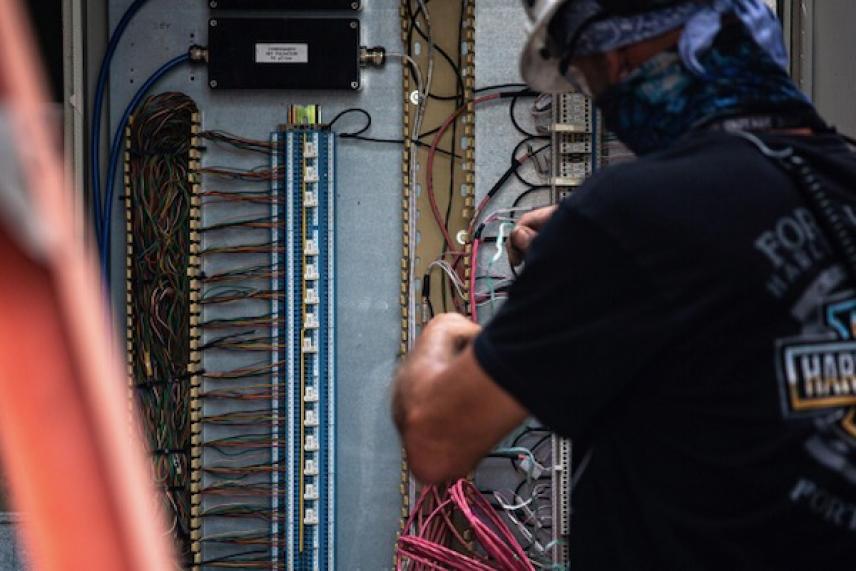 Electrician working on a control panel with multicolored wires.