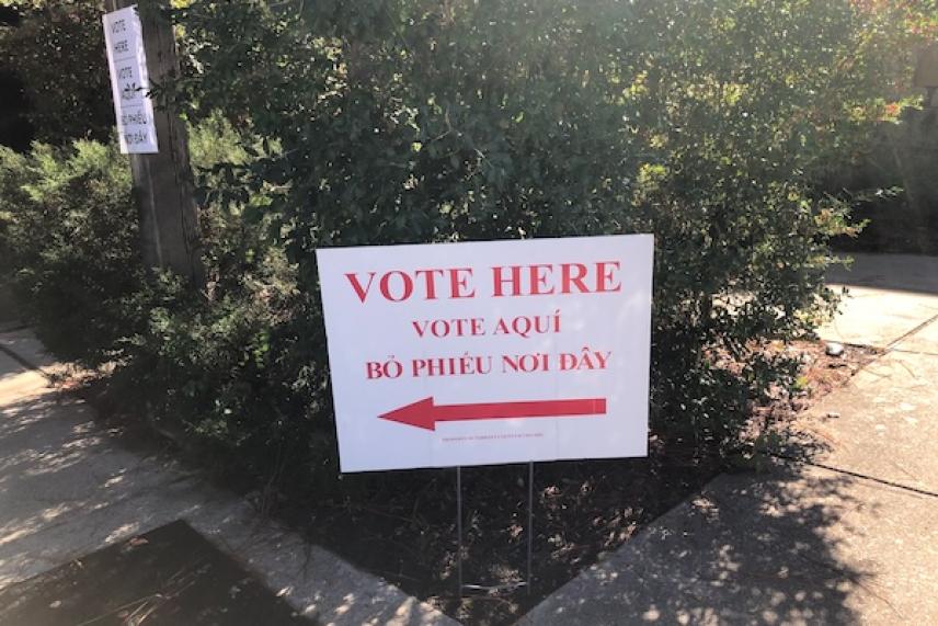 Vote here sign with a red arrow pointing left.