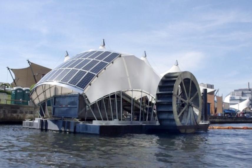 Floating solar-powered water wheel on a river under a blue sky.