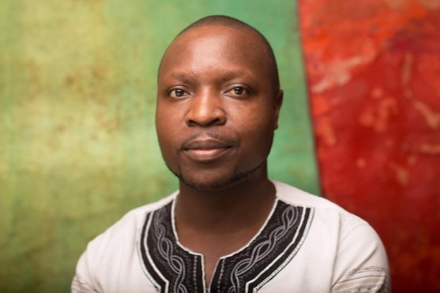 Man in white shirt with black patterns, colorful background of green and red.