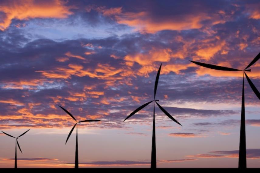 Wind turbines against a vibrant sunset sky with colorful clouds.