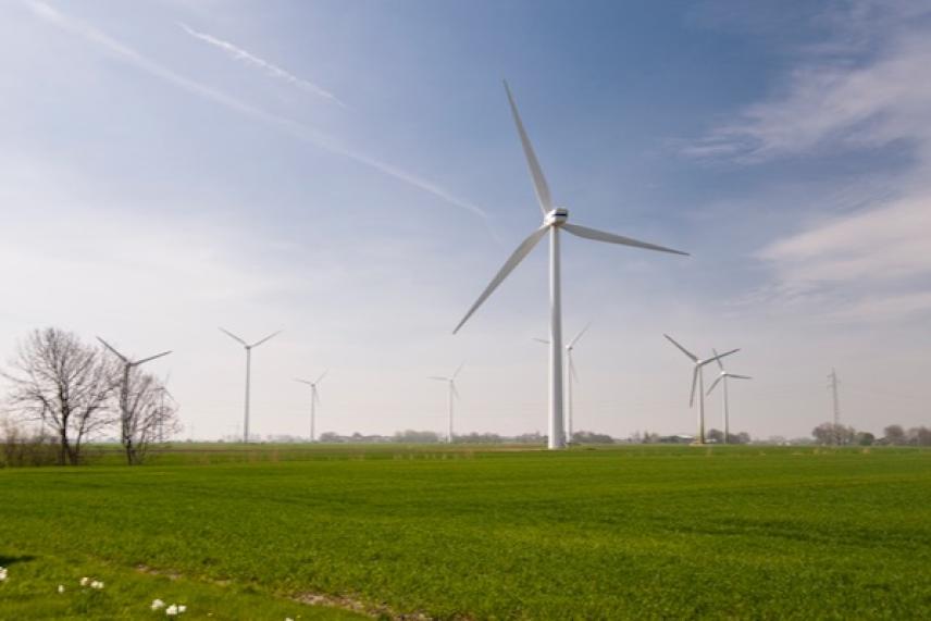 Wind turbines on a green field under a blue sky.
