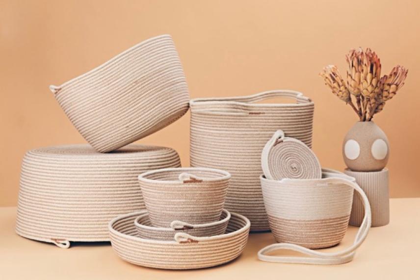 Woven baskets and a vase with dried flowers on a tan background.