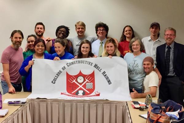 Group of people smiling, holding a "College of Constructive Hell Raising" banner.