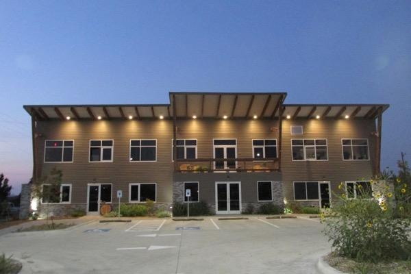 Two-story building with lights on, at dusk.