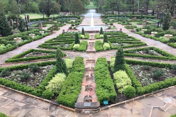 Symmetrical garden with fountain, pathways, and neatly trimmed hedges.