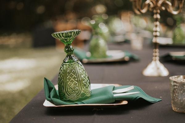Green glass upside down on napkin at elegantly set outdoor table.