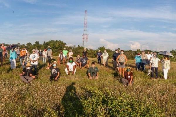 Group of people standing in a grassy field with a tower in the background.