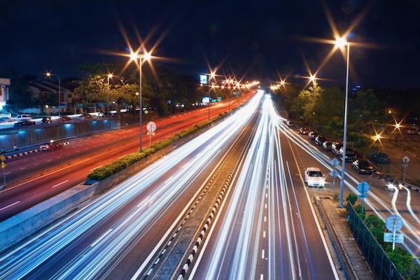 Long exposure of city highway at night with light trails from cars and streetlights.