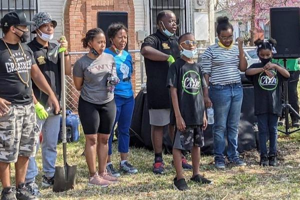 Community group outdoors planting trees, wearing masks and gloves.