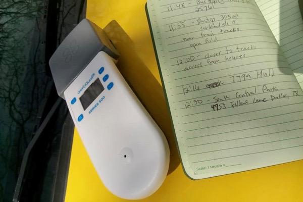 Portable device on yellow surface near open notebook.