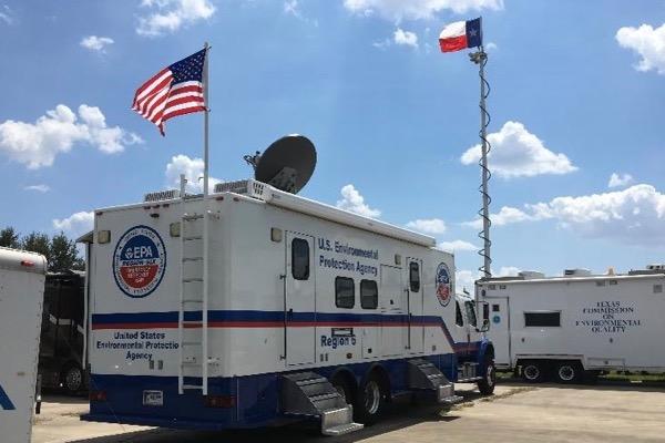 U.S. emergency response trailer with flags under a blue sky.