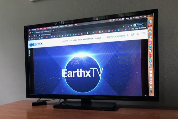 Television displaying EarthxTV website with a glowing Earth logo.