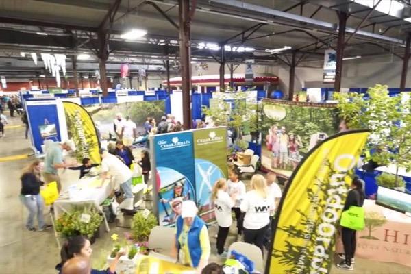 Busy trade show with colorful booths and crowds in a large indoor venue.