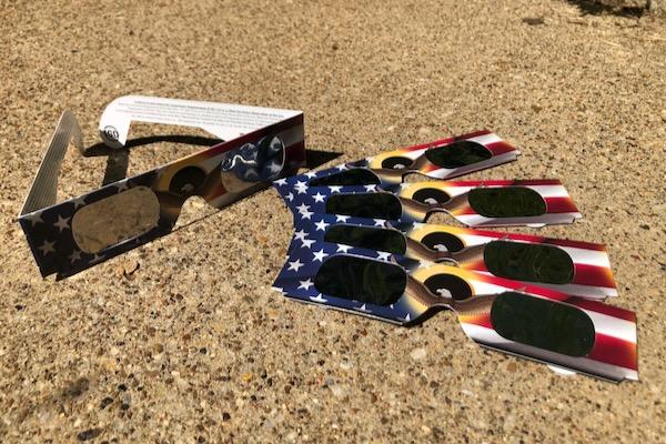 Solar eclipse glasses on a textured surface, with USA flag designs.