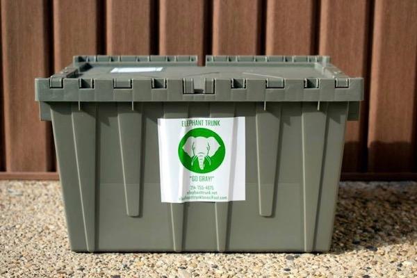 Gray recycling bin with elephant logo in front of a wooden wall.