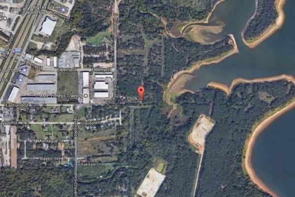 Aerial view of an industrial area beside a forest and lake.