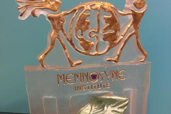 Bronze award with figures holding a globe, "Memnosyne Institute" text.