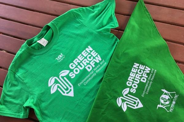 Green T-shirt and bandana with white text and leaf graphics on a wooden surface.