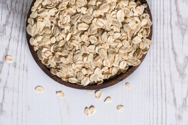 Bowl of rolled oats on a light wooden table.