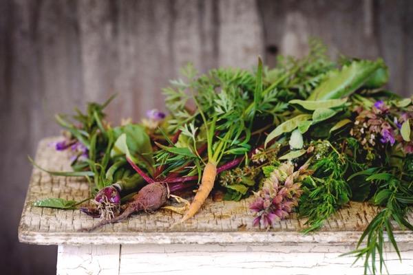 Fresh herbs and vegetables on a rustic wooden table.