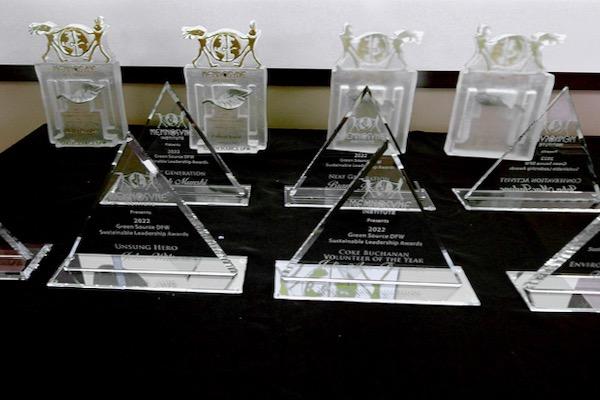 Transparent triangular and rectangular trophies arranged on a black tablecloth.