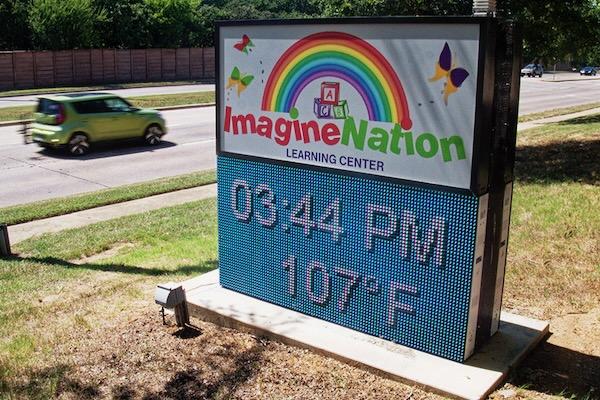 Outdoor sign displays 3:44 PM, 107°F, with vibrant rainbow and butterflies.