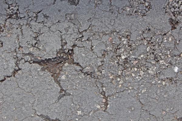 Cracked asphalt with scattered gravel.