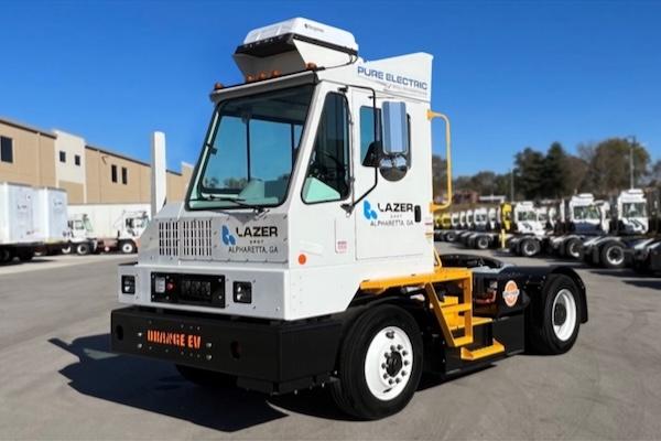 Electric truck parked on asphalt under clear blue sky.
