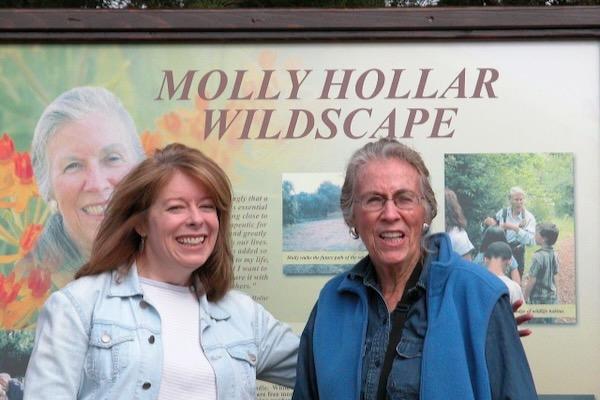 Two people smiling in front of a sign at Molly Hollar Wildscape.