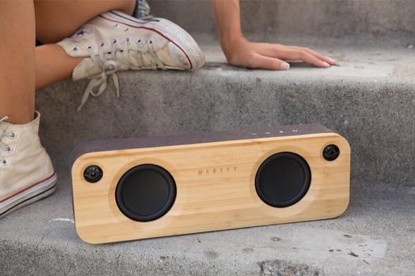 Wooden speaker on stone steps near a person wearing white sneakers.