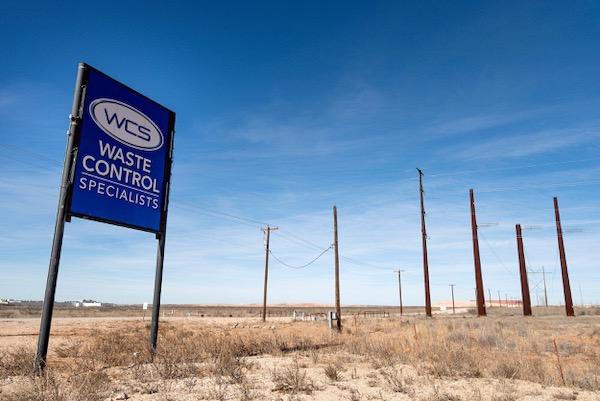 Waste Control Specialists sign in a barren, desolate landscape under a clear blue sky.