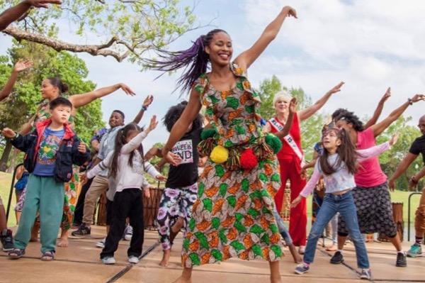People dancing joyfully outdoors on a sunny day.