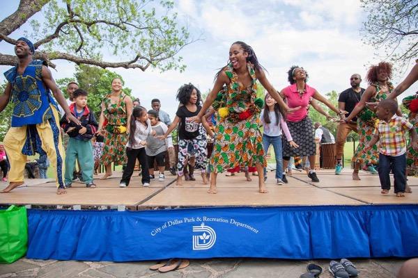 A group of people dancing energetically on an outdoor stage.