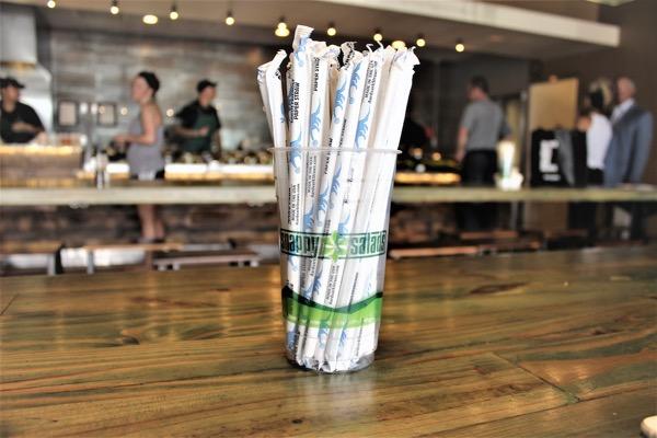 Bundle of wrapped straws on a wooden table in a coffee shop.