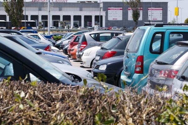 Cars parked in a busy parking lot near a building.