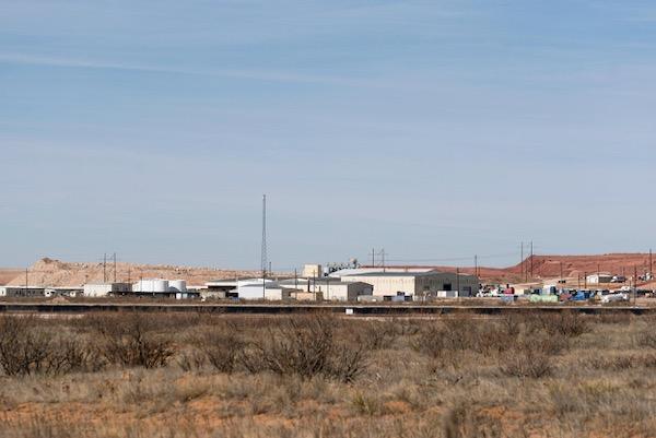 Industrial buildings in a desert landscape under a clear blue sky.