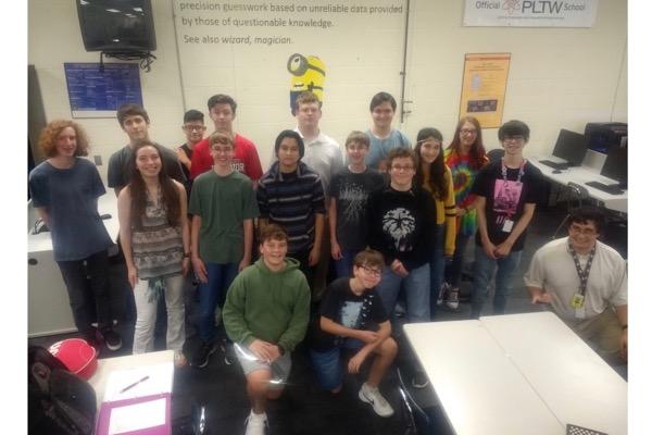 Class of students and a teacher posing in a tech classroom.