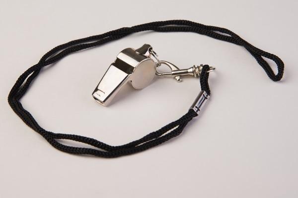 Silver whistle with black cord on a white background.