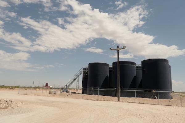 Large black storage tanks under a partly cloudy sky.