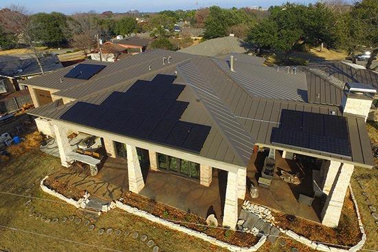 Aerial view of a large house with solar panels on the roof.