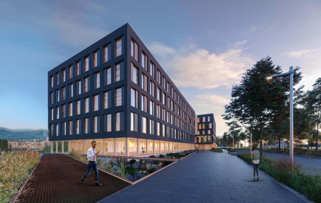 Modern building at dusk with walkway and trees nearby. Sky has scattered clouds.
