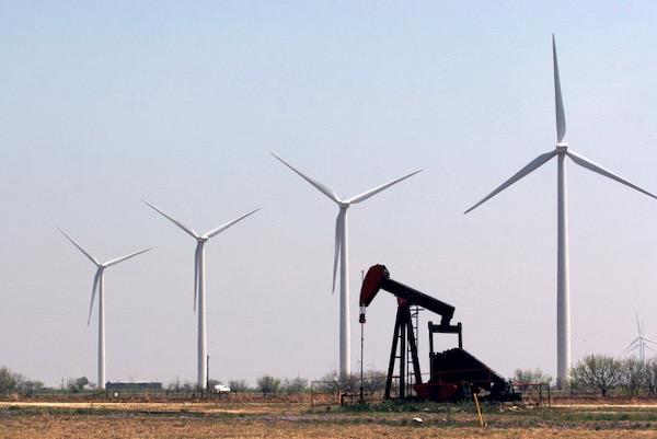 Wind turbines and an oil pump in a field under clear sky.