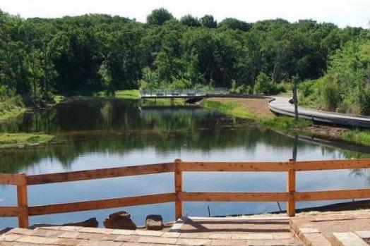 Wooden fence overlooking a calm river surrounded by lush greenery.