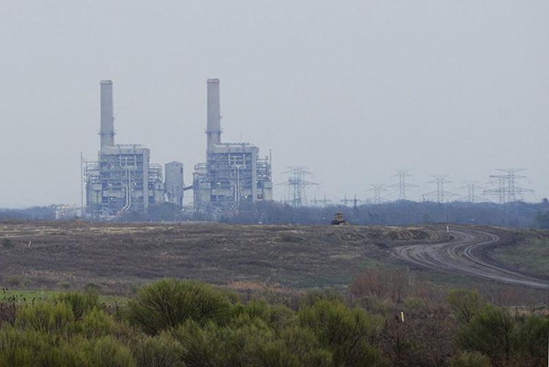 Power plant with smokestacks in a flat, open landscape.