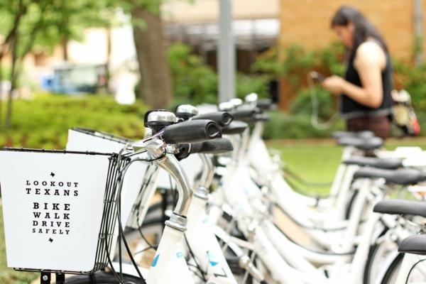 White rental bikes lined up; a person stands blurred in the background.
