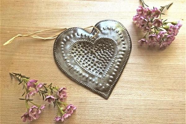 Heart-shaped metal ornament surrounded by pink flowers.