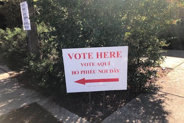 Vote here sign with a red arrow pointing left.
