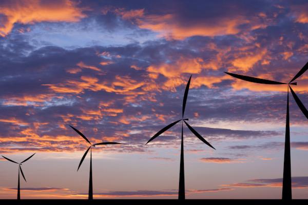 Wind turbines silhouetted against a vibrant sunset sky.